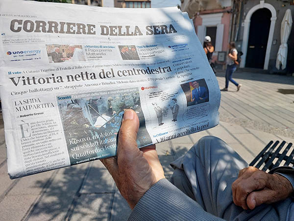 Man holding up a Sicilian Newspaper, Aci Castello, Sicily
