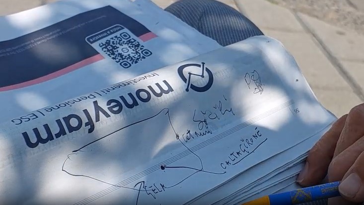man draws a map of Sicily on the day's newspaper, Aci Castello, Sicily