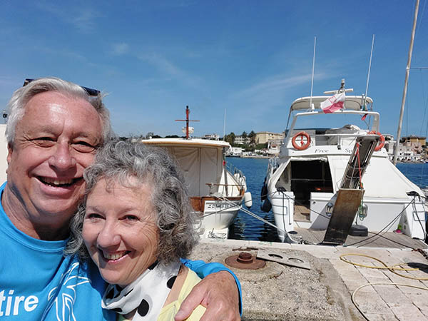 A senior couple in front of yachts at Brindisi Harbor, Italy