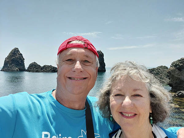 older couple in front of coastal rocks, Eastern coast of Sicily