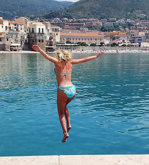 Bathing beauty jumping into the water Cefalu, Sicily