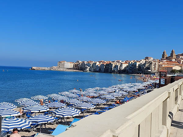 striped umbrellas lined on the beach at Cefalu, Sicily
