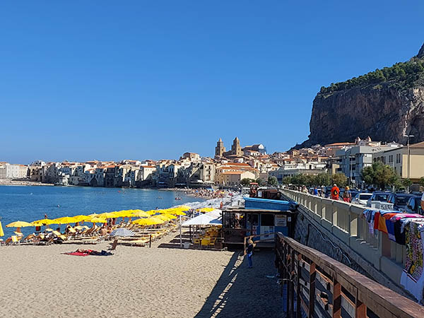 Lines of yellow umbrellas on the beach in Cefalu, Sicily