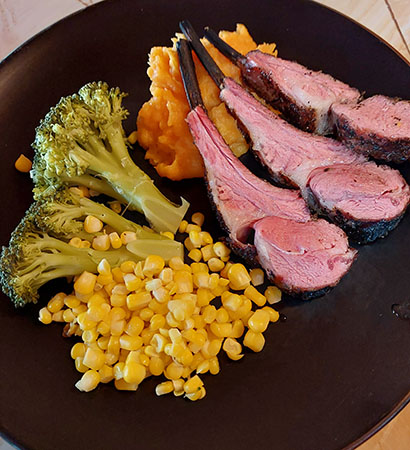 Grilld lamb chops on a bed of mashed sweet potatoes, broccoli, fresh corn