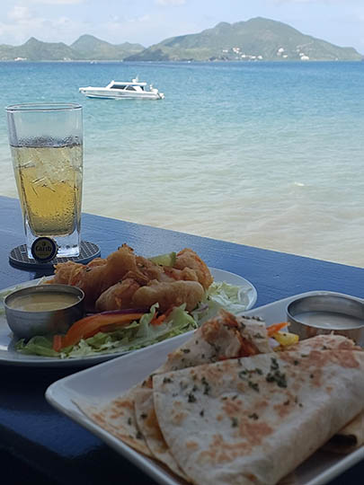 Lunch and Carib beer with boat on the sea, St. Kitts in the background from On The Rocks Bar and Lounge   
