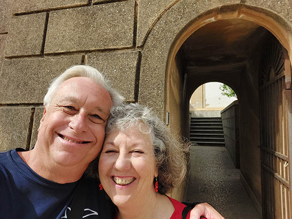 Senior couple smiling in front of an alleyway in Palermo, Sicily