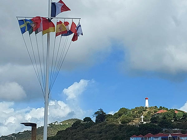 Flags at Port Gustavia with lighthouse up on the hill. St. Barth