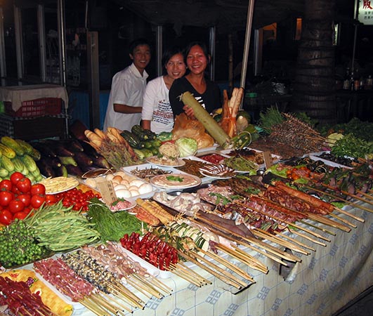 A full display of brochettes and fresh vegetables in Jinghong, China
