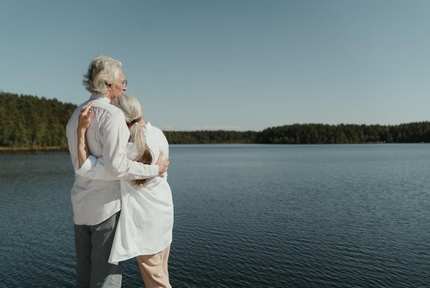 Senior couple embracing by a peaceful lake, symbolizing the freedom and serenity of moving abroad in retirement.